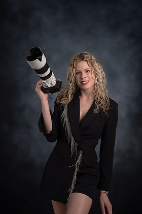 Photographer holding Camera with zoom lens attached.
