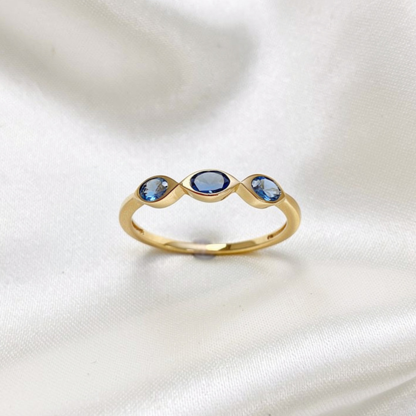 Dainty gold ring featuring three small compart stones.