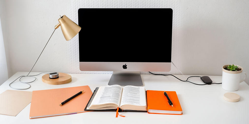, bible, notebook, computer on a desk using the colors orange on q white desk with a lapt
