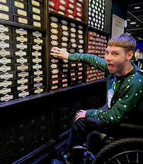 A male service user reaching out to select a wand at the shop during the Warner Bros. Stud