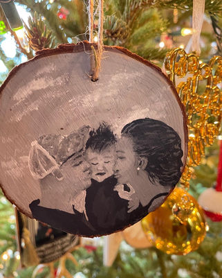 A wooden Christmas ornament with a family painted on it.
