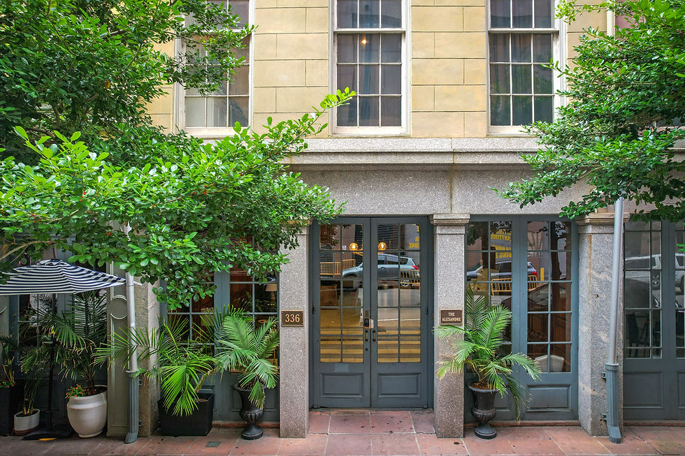 Entry of Alexandre, a CSTR building in new orleans with units for sale, colorful umbrellas striped, lush trees, new orleans CBD