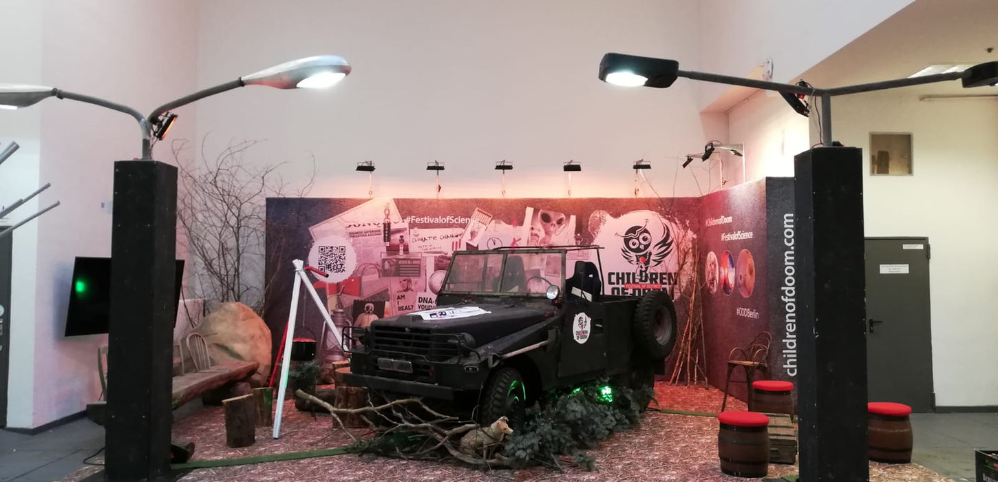 Stimmungsvolle Indoor-Event-Installation mit atmosphärischer Beleuchtung, schwarzem Fahrzeug und professioneller Soundanlage vor einer rot beleuchteten Wandgestaltung