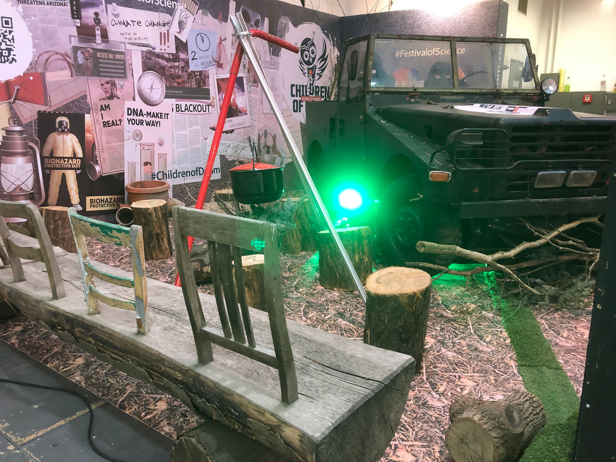 Indoor-Ausstellungsbereich mit grüner Beleuchtung, verschiedenen Displays und Informationstafeln in einem atmosphärisch gestalteten Raum