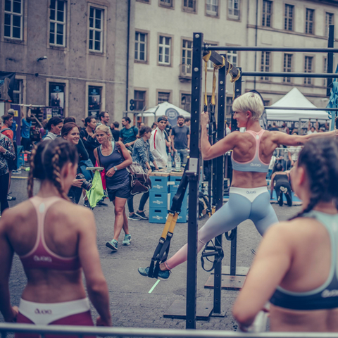 Urban Fitness Event mit Teilnehmern beim CrossFit-Training an Klimmzugstangen im Freien, städtische Sportveranstaltung mit aktiver Community
