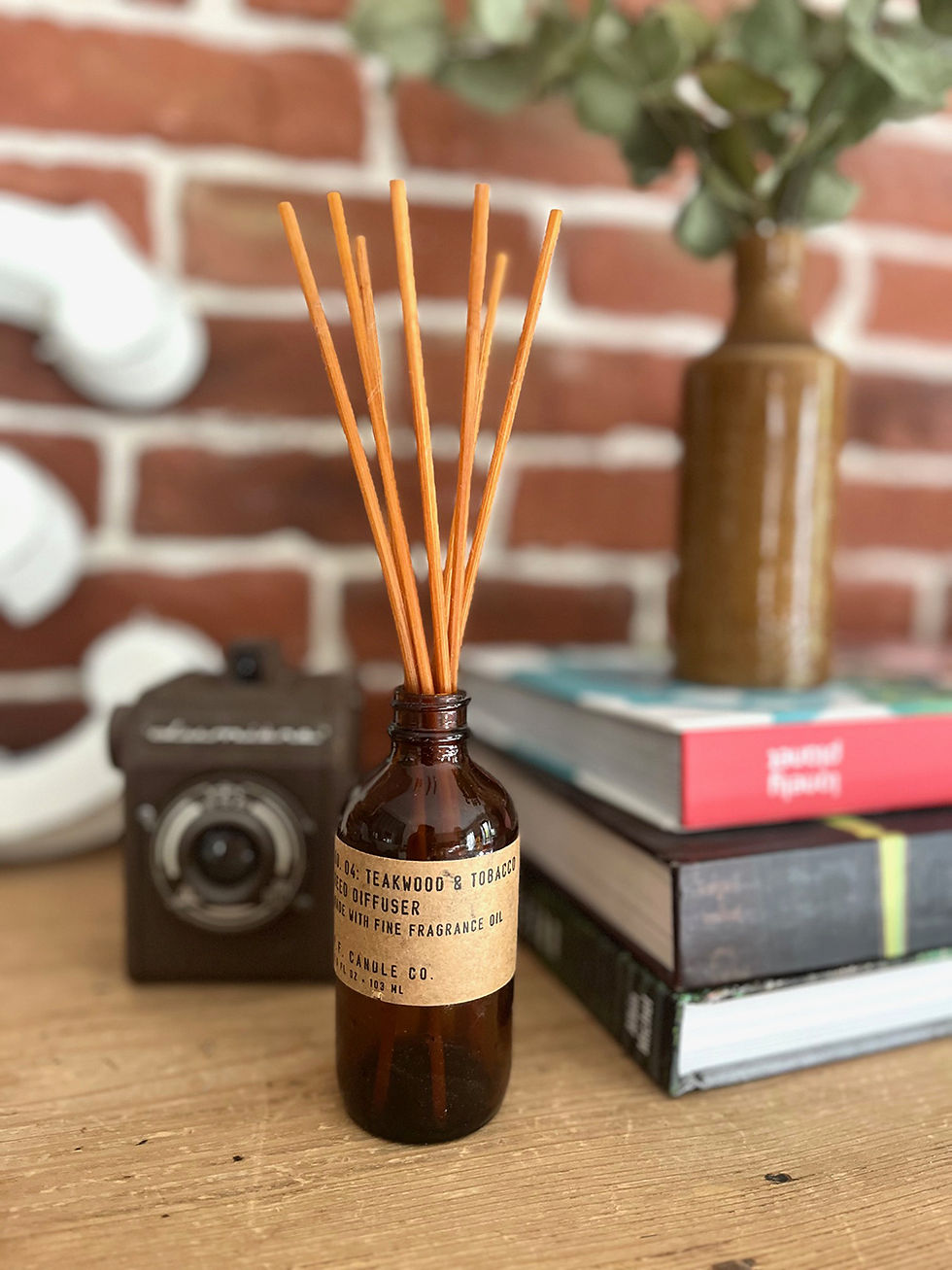 Diffuseur de parfum avec des bâtonnets et des livres en arrière-plan, unique en son genre.