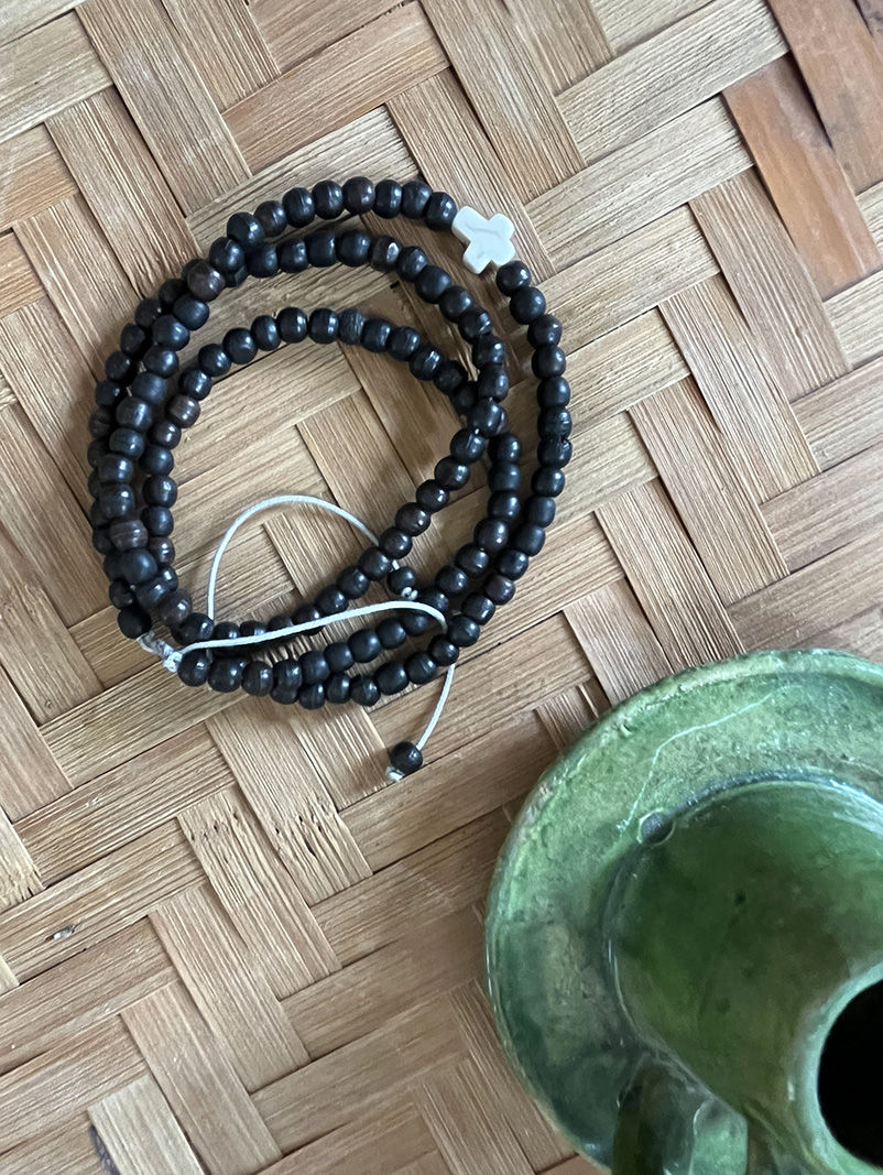 Bracelet Triple tour en perles de bois sur une surface tressée, unique en son genre.