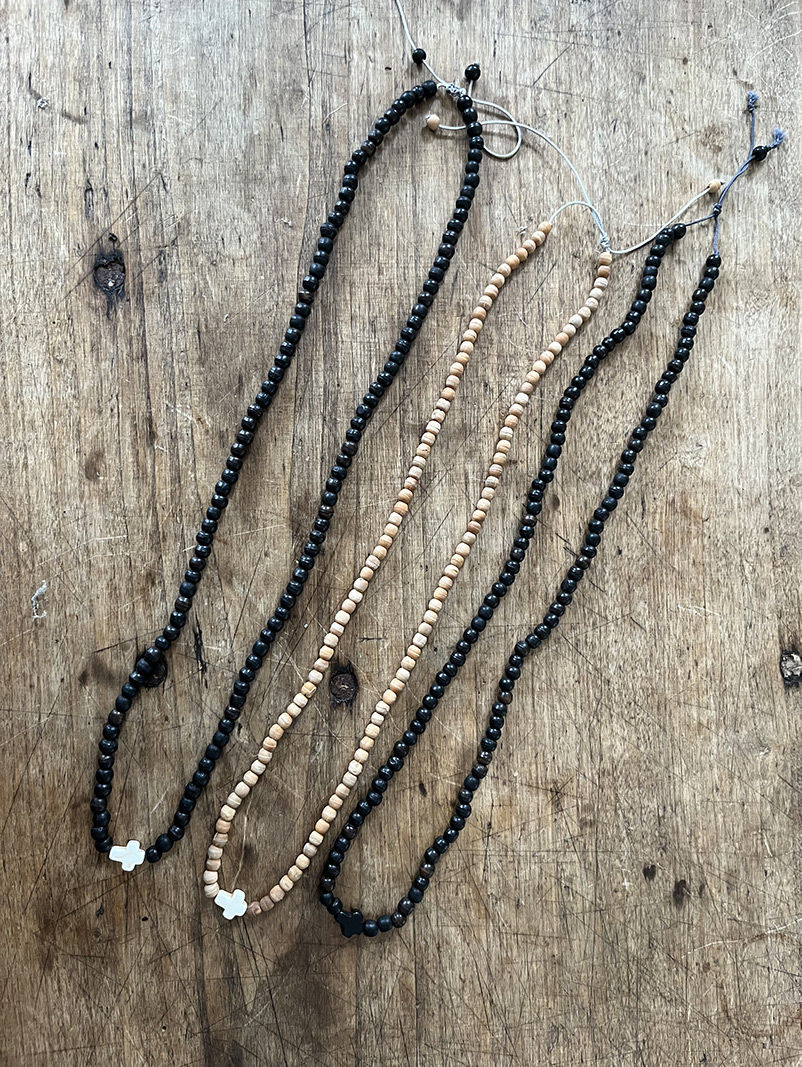 Colliers de perles noirs et dorés sur fond bois, Bracelet Triple tour en perles de bois.