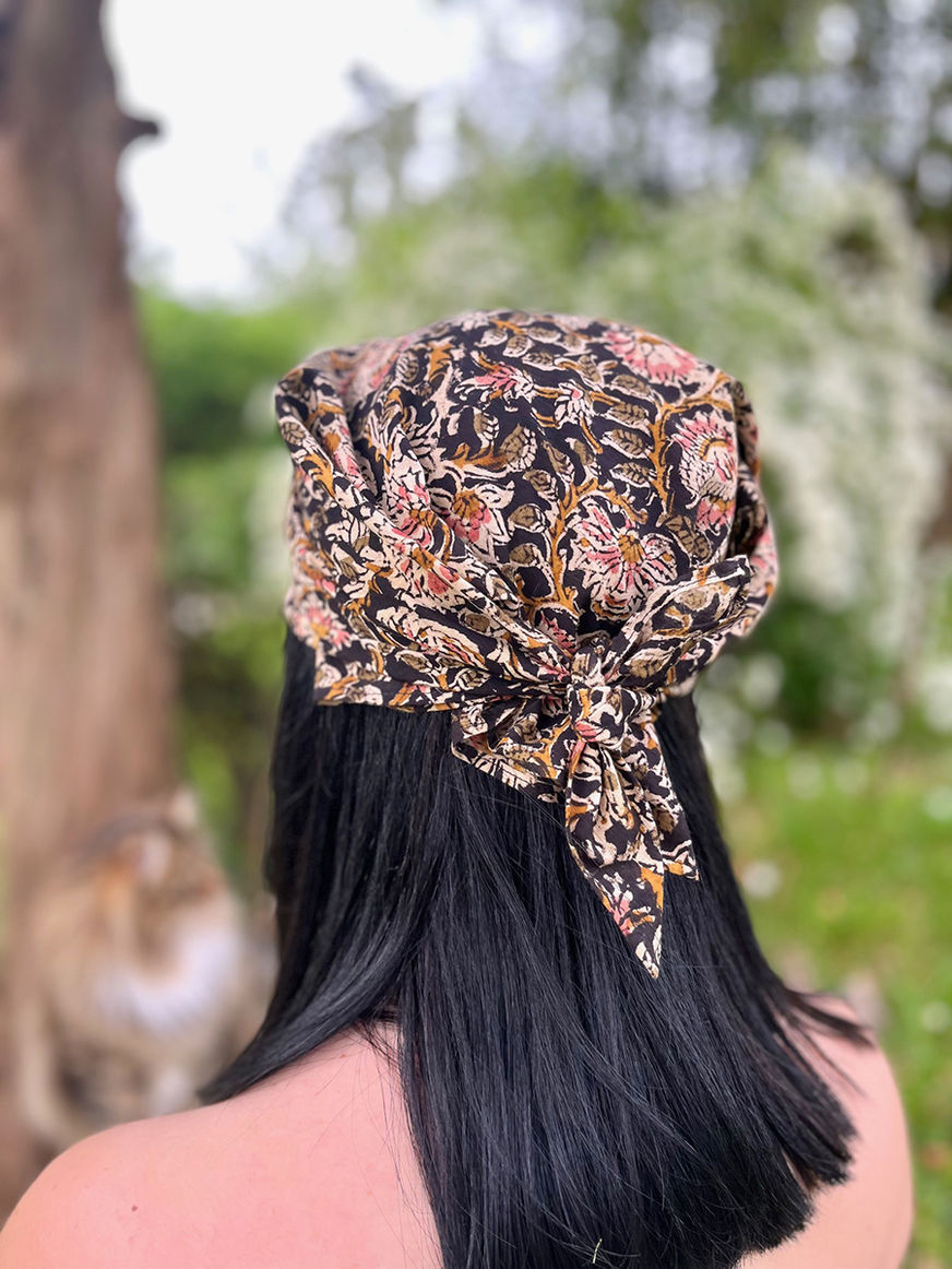 Femme coiffée d'un foulard imprimé, le dos tourné, en extérieur, Unique en son genre.
