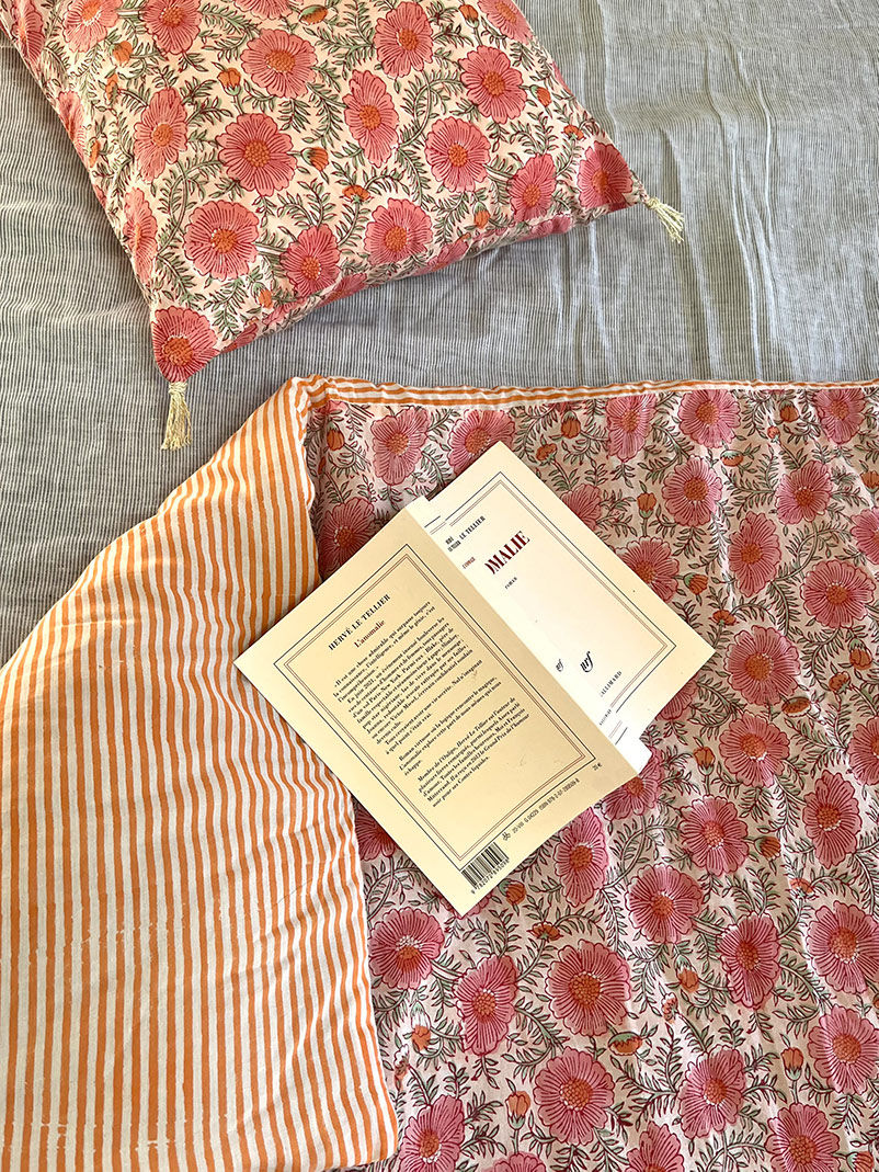 Drap de lit fleuri et oreiller floral, avec un livre ouvert, unique en son genre.