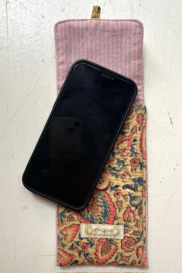 Un téléphone noir sur un étui imprimé, détail de motifs fleuris et bouton.
