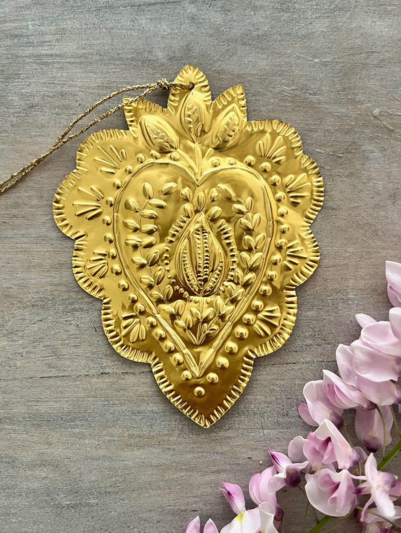 Ornement doré en forme de cœur, design floral, sur fond bois avec fleurs.