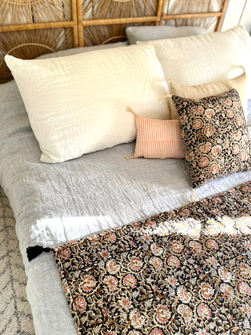 Un lit douillet avec oreillers et couverture imprimée, ambiance chaleureuse.