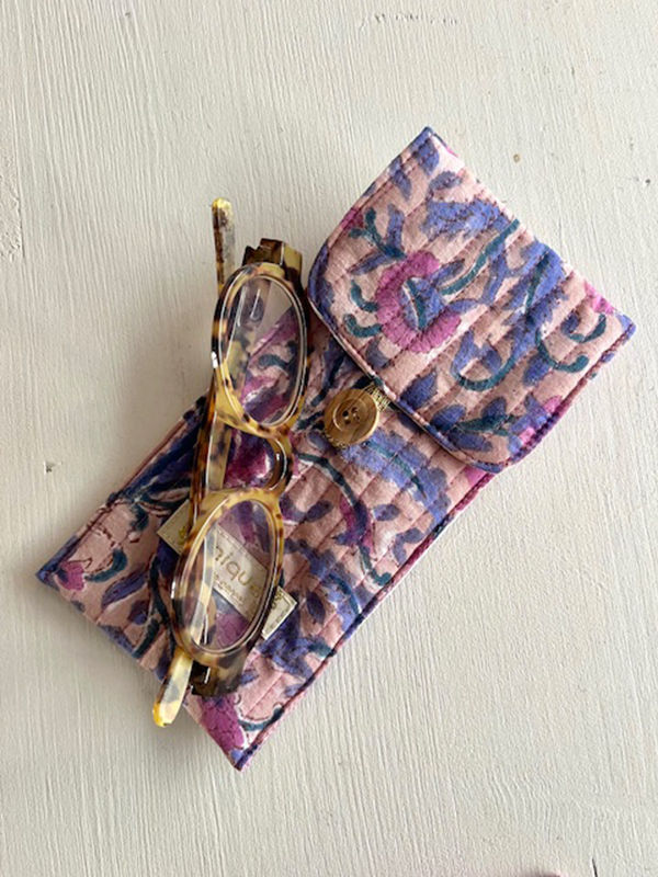 Lunettes dans un étui fleuri, sur une surface blanche, unique en son genre.