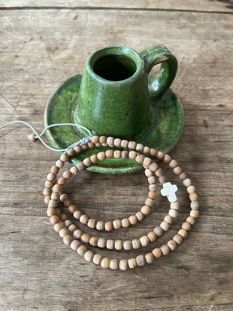 Tasse verte, soucoupe, et Bracelet Triple tour en perles de bois sur bois rustique.