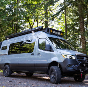 A Limitless Van Mercedes Sprinter 170 camper van conversion with safari rack and CAtuned Off-Road Front Bumper in front of a forest.
