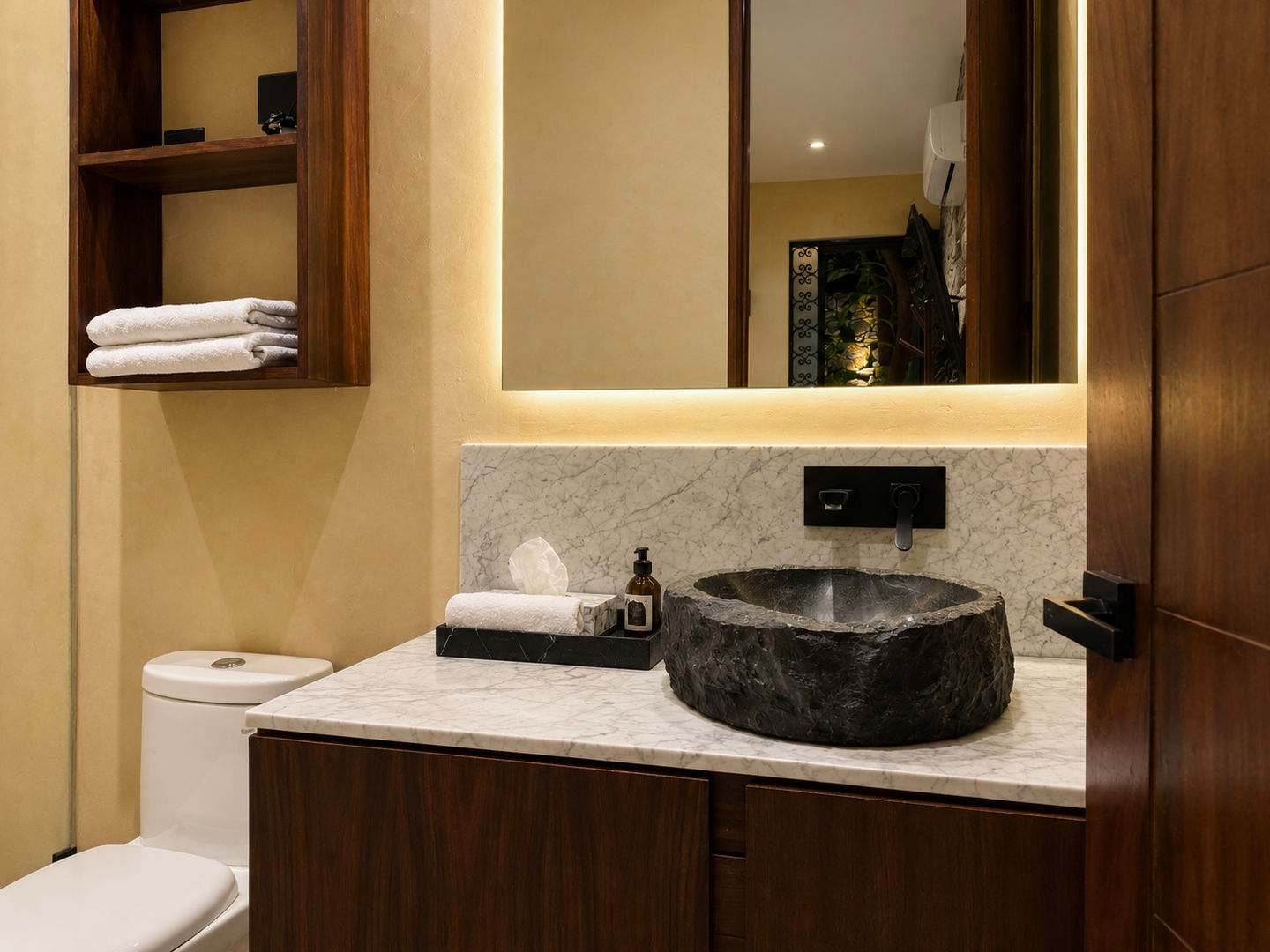 Baño de Hotel Travertino con lavabo de piedra y espejo iluminado.