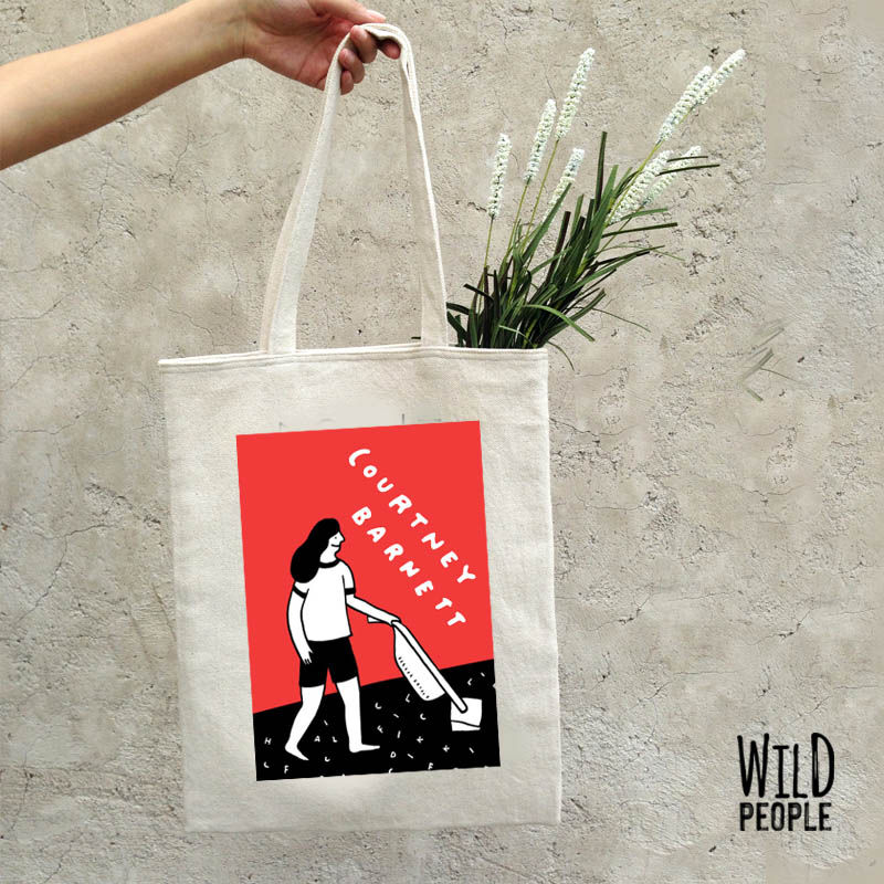 Ecobag Courtney Barnett com flores dentro, sendo segurada pela mão