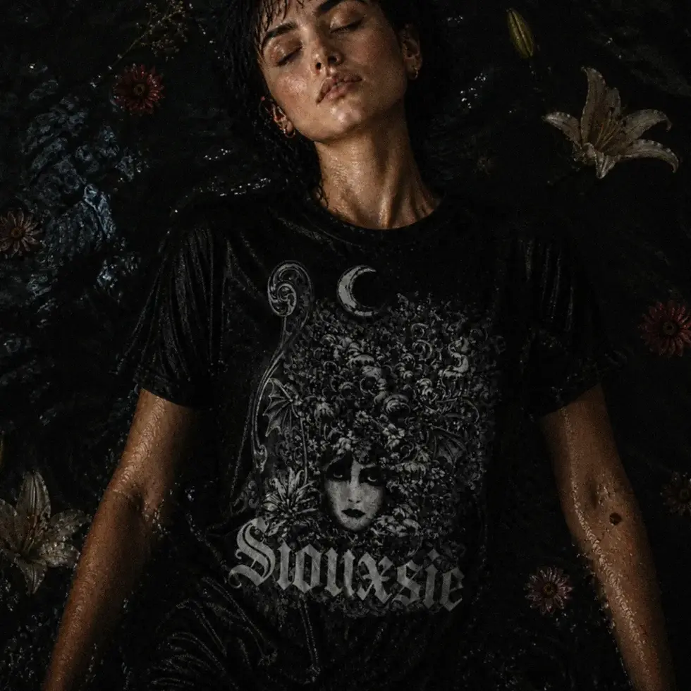 Menina de olhos fechados usando camiseta preta com estampa Siouxsie apoiada na parede com papel de parede de flores