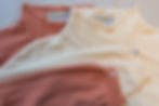 Miniaturbild: Detailaufnahme von Pullovern aus Bio-Baumwolle mit Waffelstrick in Soft Orange und Wollweiß