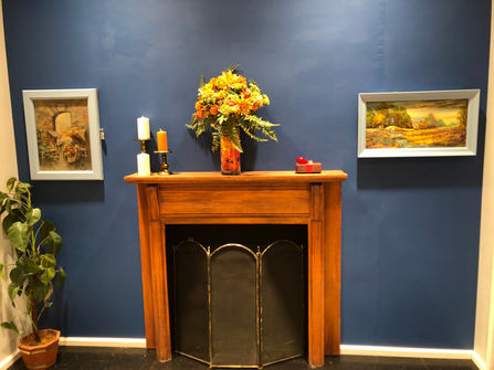 The mantle, with picture frames on either side and a bouquet of flowers and small box on top.