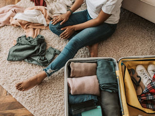 Femme assise par terre préparant sa valise ouverte avant un voyage en Polynésie