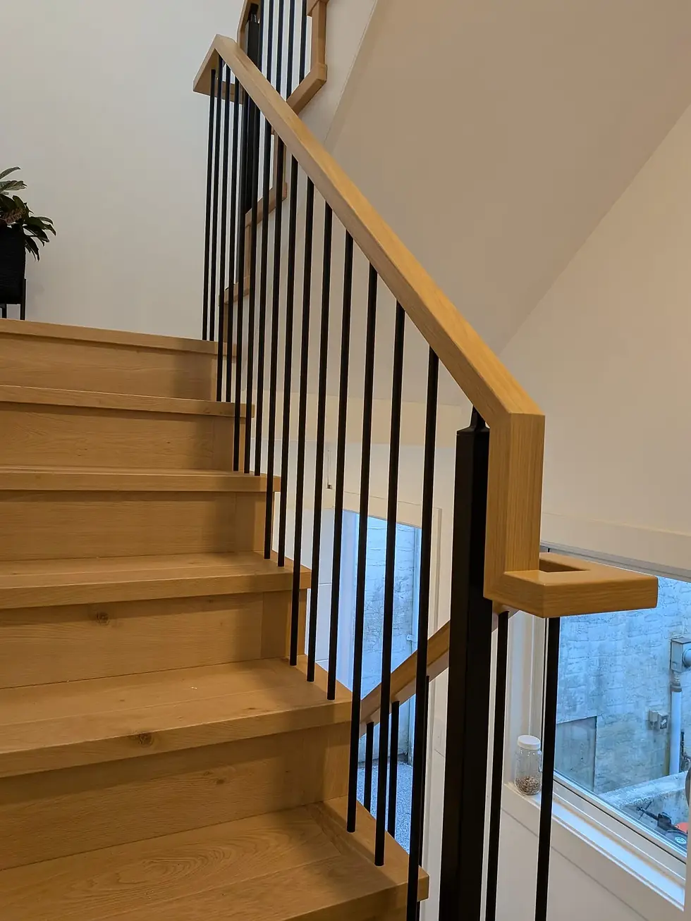 Interior stair railings with wood handrail and black metal balusters on wood treads