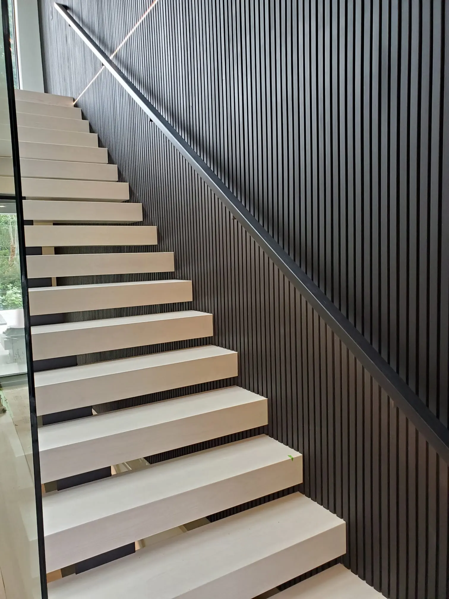 Minimalist interior straight stairs with open risers and sleek black metal stair railing in a modern home