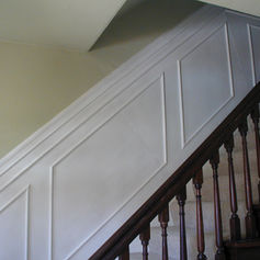 Traditional wood staircase bannister with white paneling in a San Francisco home. 