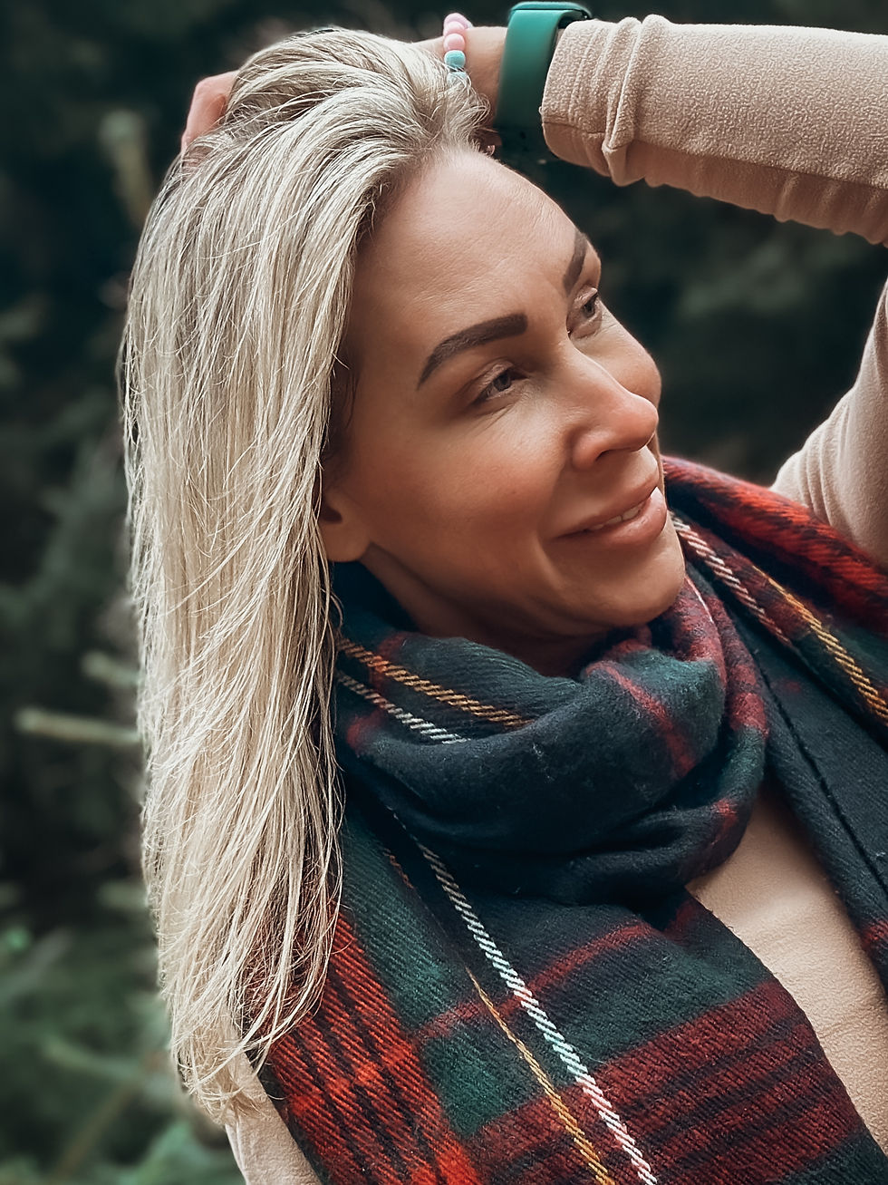 A portrait of a smiling woman in a beautiful forest on a crisp autumn day in the Lake District. The vibrant fall foliage surrounds her, creating a warm and inviting atmosphere.