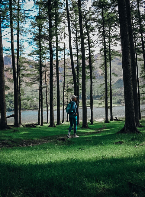 Lakeside on a sunny summer day, lady standing next to the lake and enjoying the view of nature