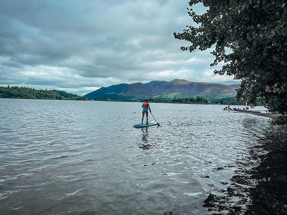 Lake panorama with mountains in the background, warm summer day, calm water and laid on sup board paddling through the lake