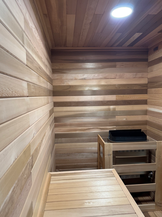 Custom cedar sauna interior with smooth sanded benches and walls during final finishing stage of sauna construction in Edmonton.