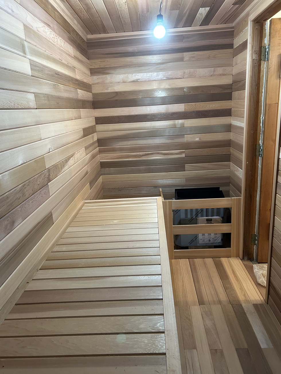 Cedar sauna interior with bench and heater installed before final electrical work.