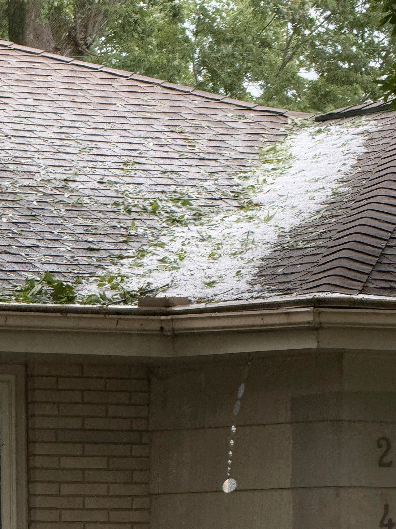 An image of a long layer of hail in the valley of a roof.