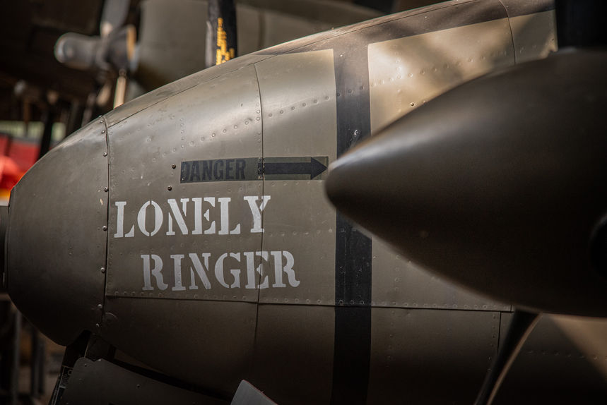 The nose of a military plane with "Lonely Ringer" painted in white on it.