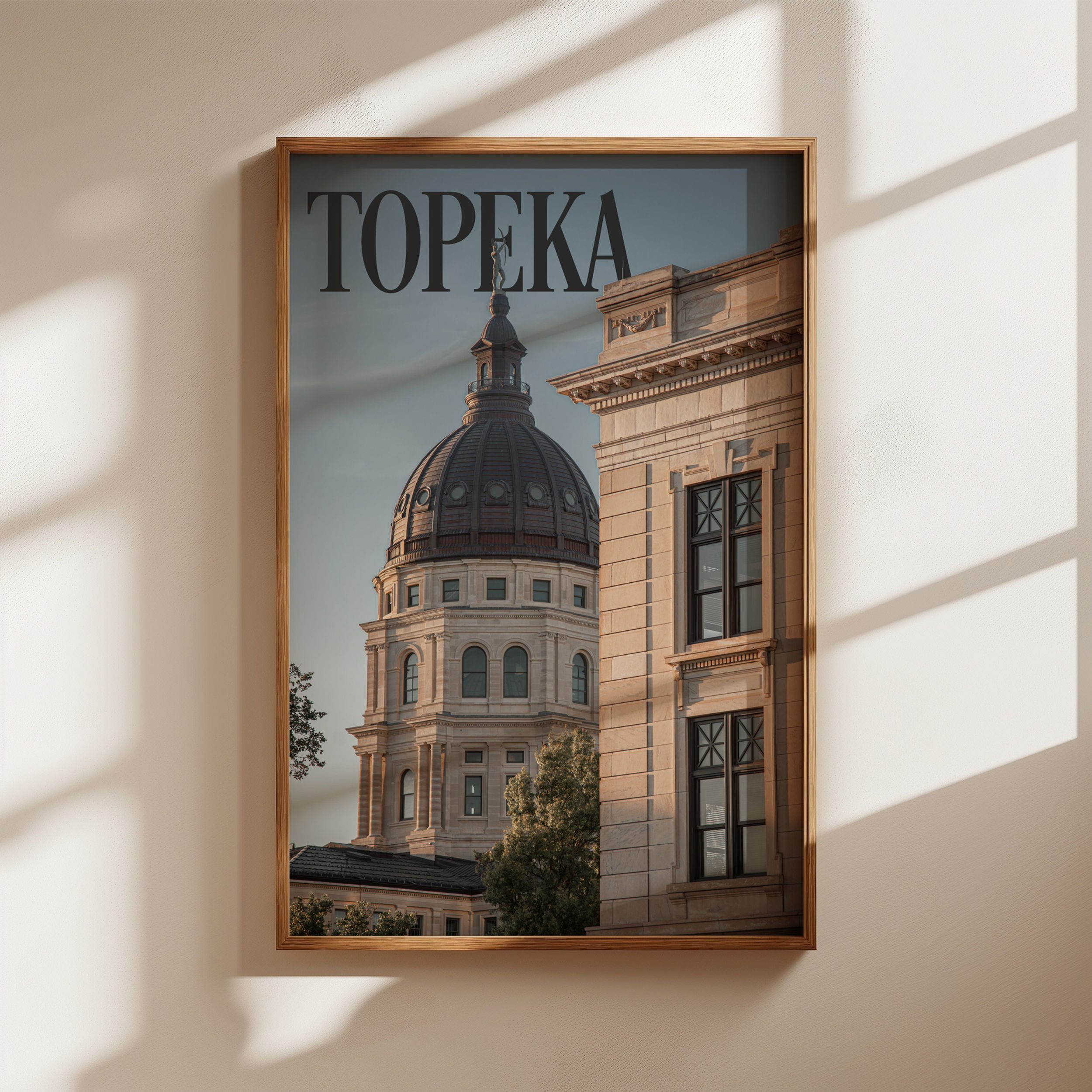A framed image of the Kansas Statehouse at sunset hangs on a wall. A Topeka editorial print.