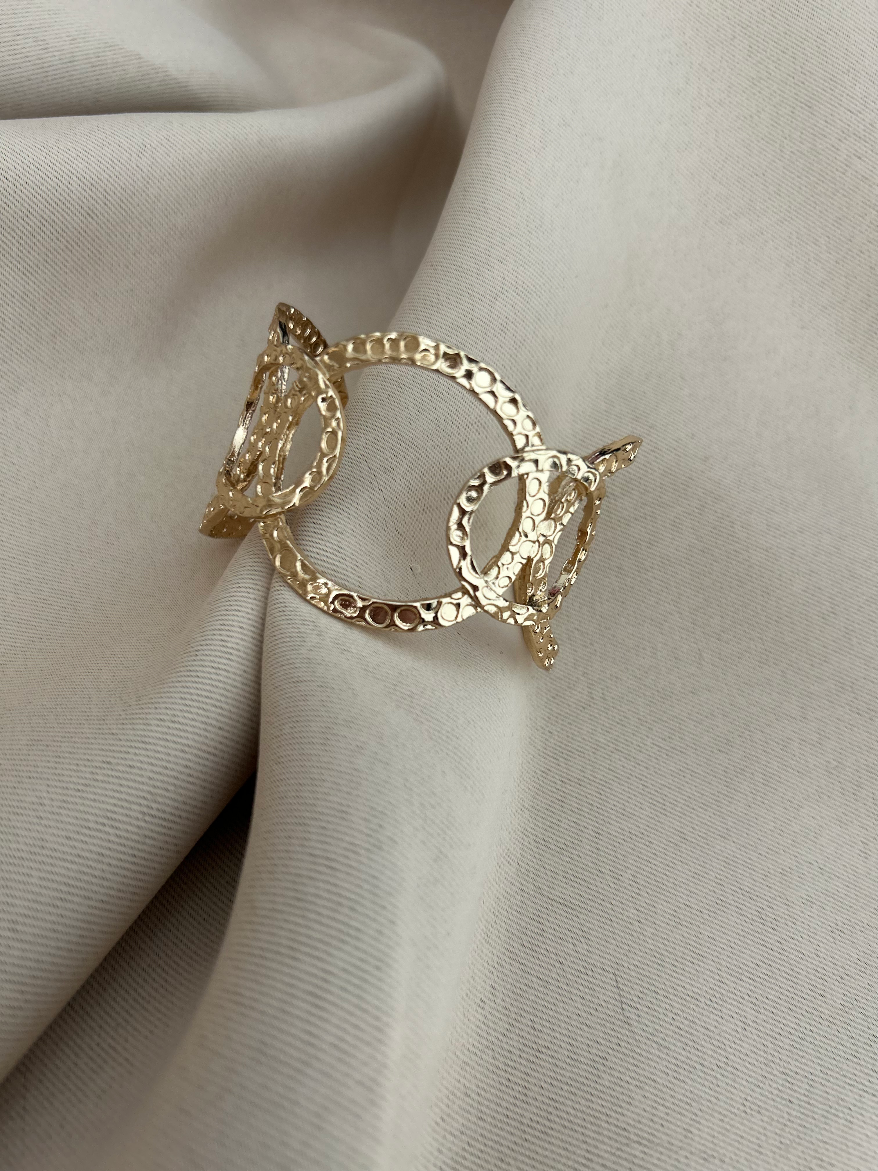 Un bracelet manchette argentée au design moderne, mêlant une large bande brillan