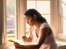A woman reflecting as she writes
