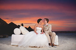 bride and groom at sunset on bech sitting smiling at each other