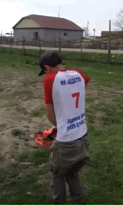 Man holding business end of chainsaw between his legs and pulling the start chord