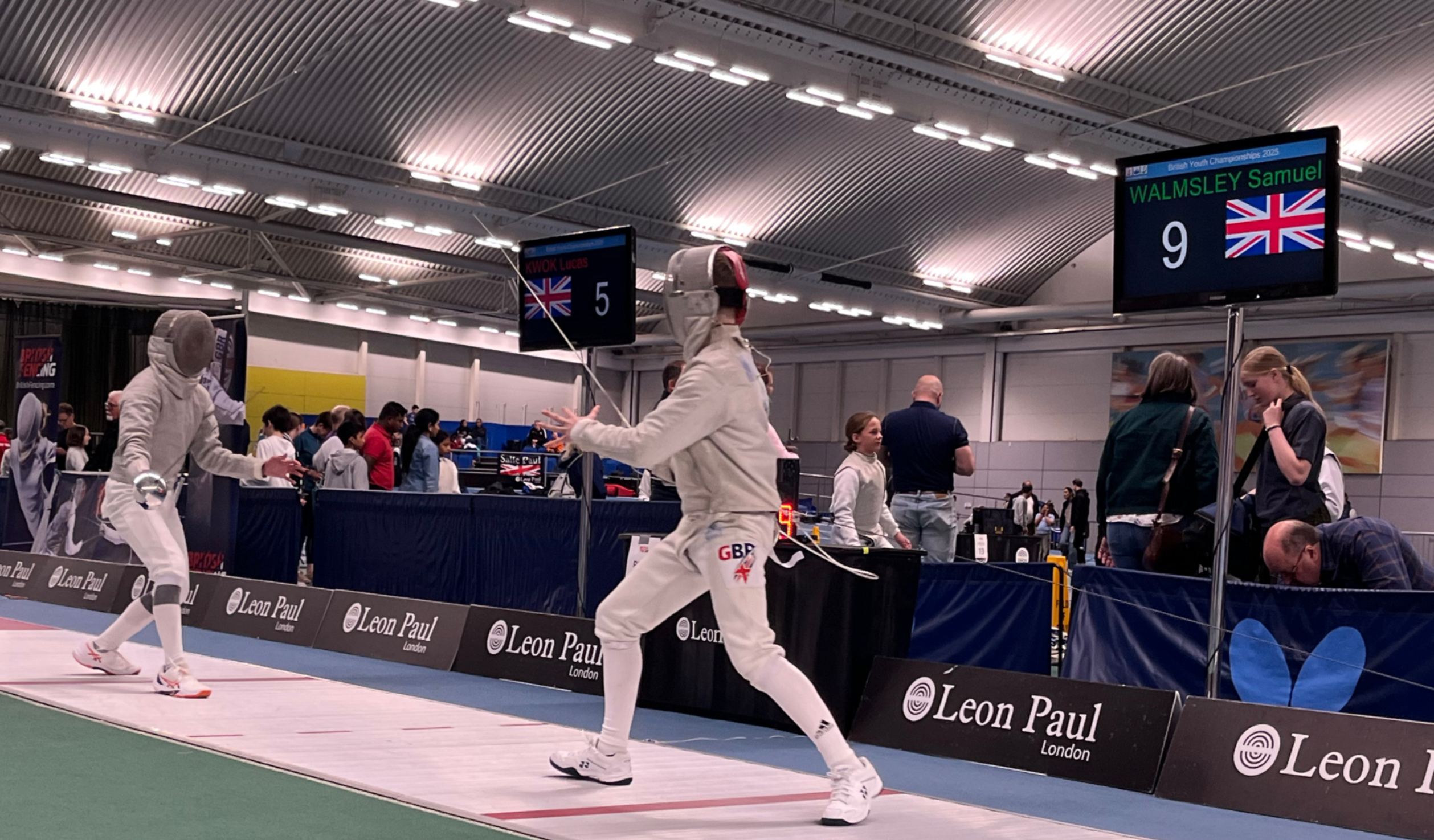A close-up of a modern electronic fencing scoring board in a sharp indoor gym.