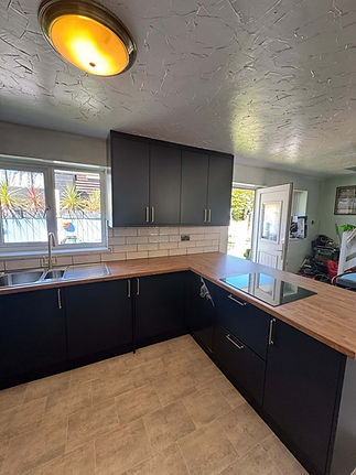 Navy fitted kitchen with wooden worktops and part-glazed door