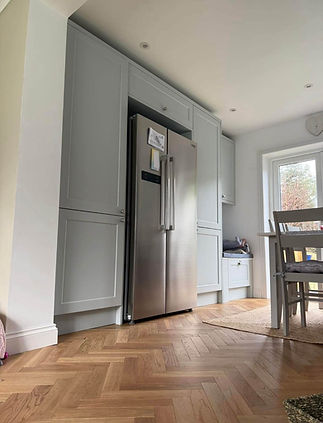 Grey fitted kitchen with integrated fridge freezer and herringbone flooring