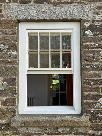 White sash window fitted into a traditional stone cottage wall