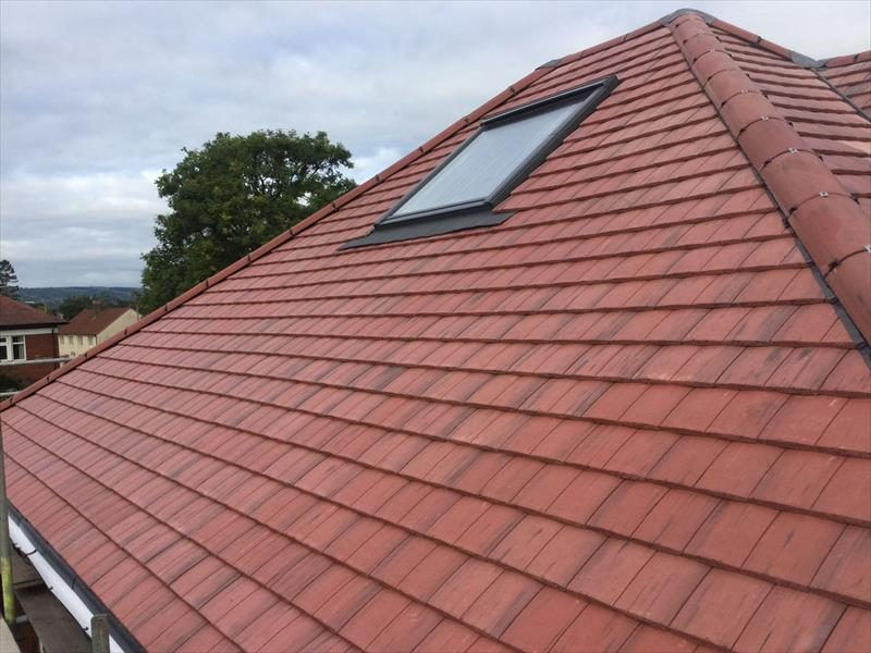 Newly tiled roof with skylight window on hipped pitched roof