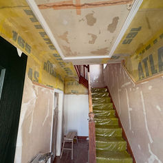 Stairs covered in protective sheeting beneath freshly plastered walls