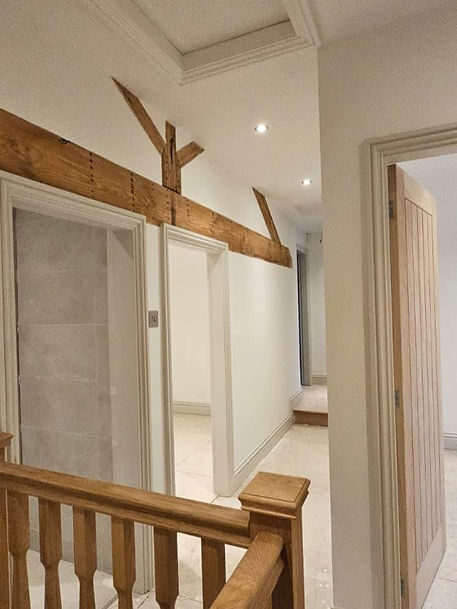 Hallway with smooth plastered walls, white doors and exposed timber beams