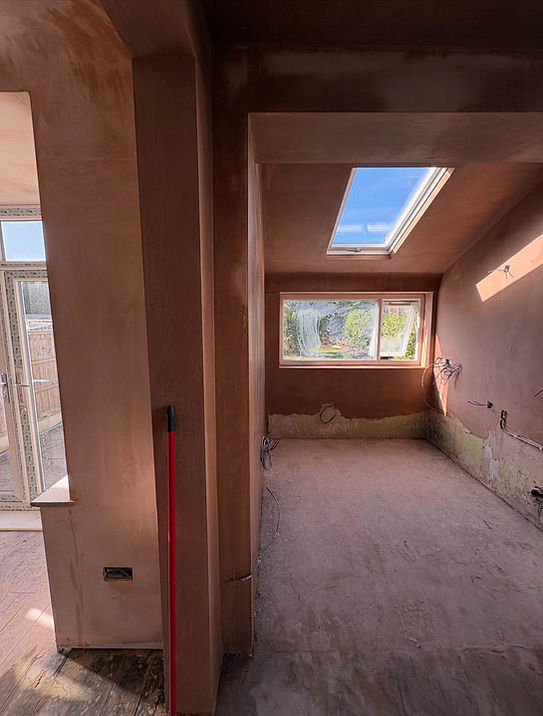 Room with rough plastered walls, exposed wiring and a window awaiting plastering in Liverpool