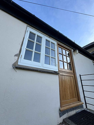Timber front door and window fitted on a white rendered cottage